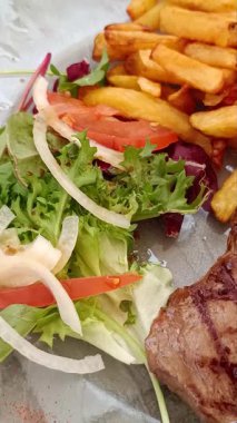 Lezzetli ızgara biftek, patates ve salata.