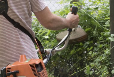 Bir çim biçme makinesiyle bahçedeki çimleri biçiyor.