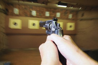 Atış poligonunda hedef nişancı, kapalı alanda silahlı spor yapıyor.