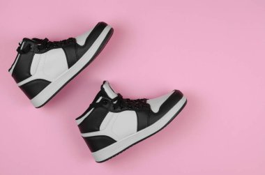 Pembe arka planda siyah beyaz spor ayakkabılar, üst manzara. Ayakkabı mağazası reklamı için şık yeni ayakkabılar.