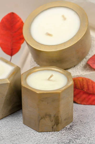 Decorative candles in golden pots and red autumn leaves, minimal composition