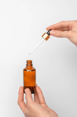 Bir kadın gerekli yağlı bir şişe ve pipet tutuyor. Kadın ellerinde serum olan kozmetik şişesi.
