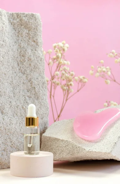 天然石の背景に美容液やエッセンシャルオイル フェイシャルマッサージ用スクレーパー付きの化粧品ボトル ロイヤリティフリーのストック画像