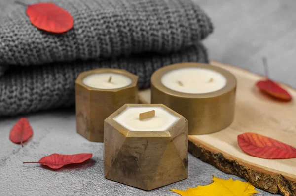 Candles in golden pots and red autumn leaves, minimal composition. The concept of home warmth and comfort