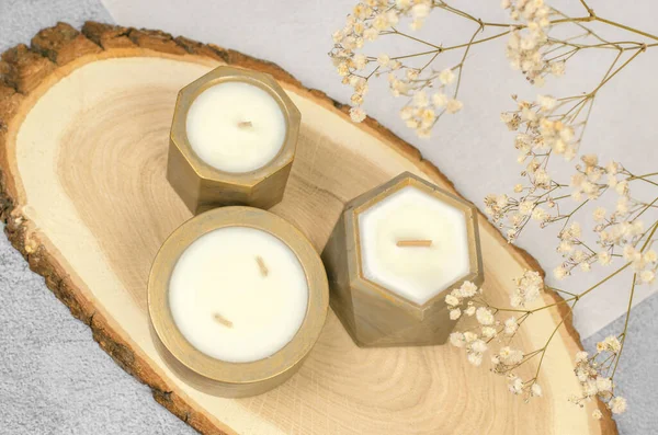 Scented candles on a wooden stand. Soy wax candle and gypsophila sprig