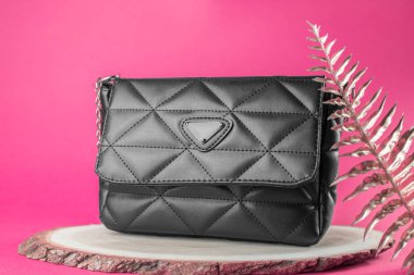 Siyah kadın çantası, minimalizm. Pembe arka planda şık bir kadın çantası.