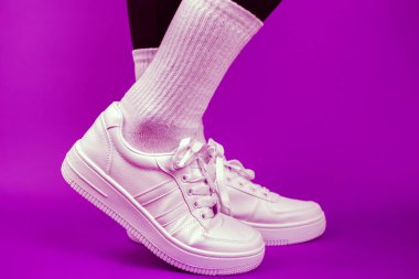 Beyaz spor ayakkabılı kadın bacakları, arka plan, mor arka plan.