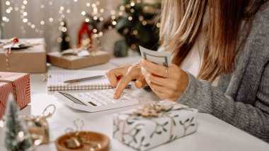 Kız Amerikan dolarlarını sayıyor, hesap makinesi kullanıyor ve masrafları yazıyor. Bütçeyle uğraşan bir kadın, alışveriş çılgınlığı için para dengesini hesaplıyor. Vergi ödeyen kadın muhasebeci. Kız Noel hediyelerini sayıyor.