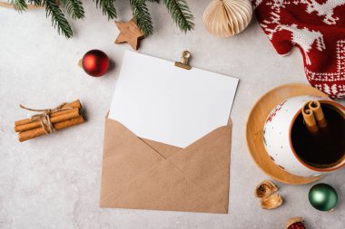 Noel tebrik kartı için boş Mockup kâğıdı. Gri arkaplan, bir fincan kahve, köknar dalı, hediye, zarf ve Noel süslemesi. Üst görünüm maketi yap ve metin için alanı kopyala.