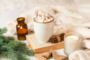 Hygge fincan sıcak kakao ya da şekerli kahve, kazak, mum, kitap, tarçın ve köknar ağacı. Noel ışıkları rahat arka plan. Noel tatili ahşap yıldız süslemeleri.