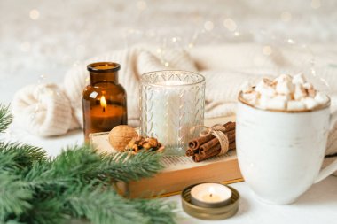 Hygge fincan sıcak kakao ya da şekerli kahve, kazak, mum, kitap, tarçın ve köknar ağacı. Noel ışıkları rahat arka plan. Noel tatili ahşap yıldız süslemeleri.