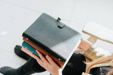 Genç kadınların el ele tutuşup not defterlerini tuttukları kesikli bir resim. Kız, tahta bir sandalyede otururken elinde bir yığın defter tutuyor. Boş alan modelleme kitapları.