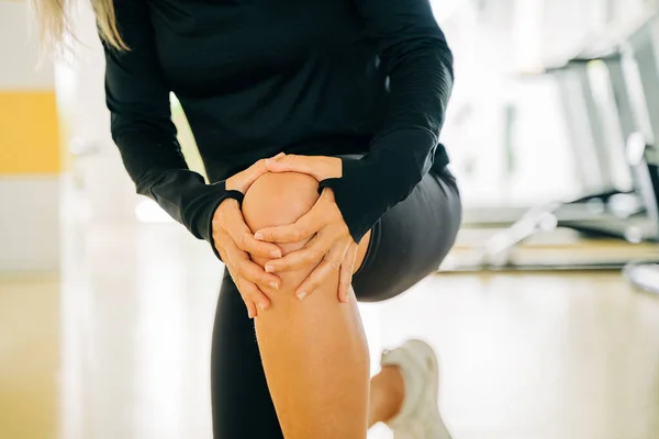 부상당 여성은 근육통을 통증을 느끼며 무릎을 스포츠 통증을 벤치에 스톡 사진