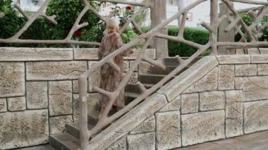 Mutlu yetişkin kadın portresi. Tropik bir tatil köyünde dinleniyor ve yürüyor. Güzel, zarif, Kafkas kıdemli kadın yaz tatilinin tadını çıkarırken limonata kokteyli içiyor..