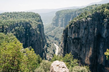 Dağ vadisi kanyon kayalıkları ve taştan nehir yolu manzaralı. Dağ sırtları, yeşilliklerle kaplı kayalar..