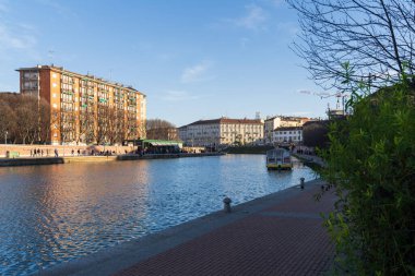 Milan,Italy-January 05,2023:People walk along the shore of the Naviglio Milanese canal and relax in the pubs,Milan,Italy.