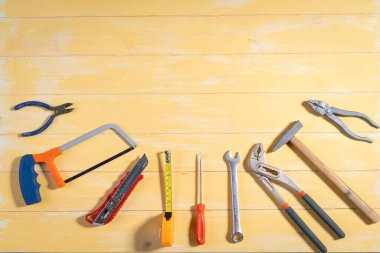 Screwdriver,hammer,tape measure and other working tools on yellow wooden background with copy space,industry engineer tool concept.still-life.