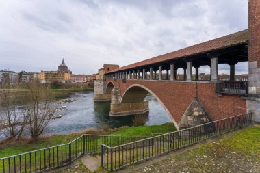 Pavia 'nın ufuk çizgisi, Ponte Koperto (üstü kapalı köprü), bulutlu bir günde, Pavia Katedrali' nin arka planında, İtalya 'da Ticino Nehri üzerinde yer alan bir köprüdür.