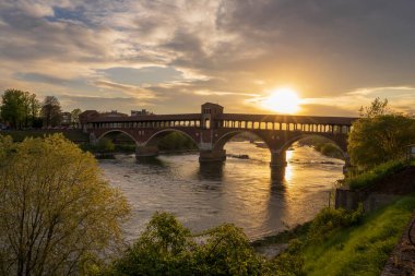 Ponte Coperto (üstü kapalı köprü) Pavia 'daki Ticino Nehri üzerinde gün batımında, Lombardy, İtalya.