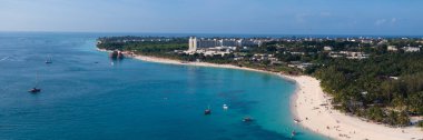 Güneşli bir günde kıyı şeridi manzarası, kumlu sahil drone manzarası, turkuaz okyanus, palmiye ağacı, lüks tatil köyü ve insanlar, Zanzibar, Tanzanya