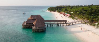 Güneşli bir günde kıyı şeridi manzarası, kumlu sahil drone manzarası, turkuaz okyanus, palmiye ağacı, lüks tatil köyü ve insanlar, Zanzibar, Tanzanya