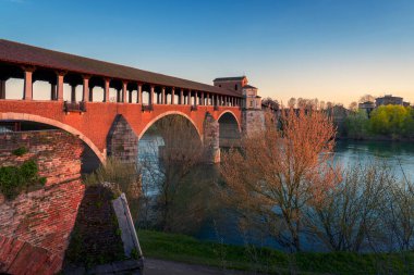 Ponte Koperto 'nun muhteşem manzarası (üstü kapalı köprü) Pavia, Lombardiya, Pavia, İtalya' da Ticino nehri üzerinde gün batımında bir köprüdür.