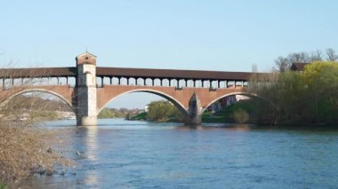 Ponte Koperto (üstü kapalı köprü), güneşli bir günde Pavia 'da Ticino Nehri üzerinde bulunan bir köprüdür.