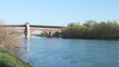 Ponte Koperto (üstü kapalı köprü), güneşli bir günde Pavia 'da Ticino nehri üzerinde bir köprü, kano üzerinde giden bir adam, Pavia, İtalya