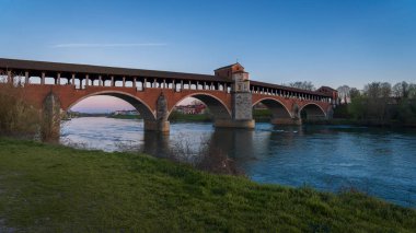 Ponte Koperto 'nun güzel manzarası (üstü kapalı köprü), Pavia' da gün batımında Ticino Nehri üzerinde yer alan bir köprüdür.