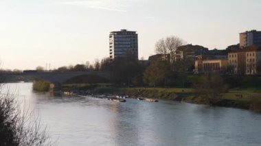 Pavia 'da gün batımında Ticino Nehri üzerindeki köprünün muhteşem manzarası, arka planda şehir silüeti, Lombardy, İtalya.