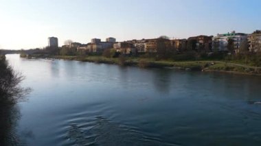 Günbatımında Pavia şehrinde Ticino nehri üzerinde harika bir köprü manzarası, arka planda şehir silüeti, Lombardy, İtalya.