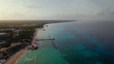 Dominicus sahilinin sabahki hava manzarası, kristal berrak deniz, güzel kumlu sahil ve arka plandaki deniz feneri ve rıhtım, Karayip Denizi. Bayahibe, Dominik Cumhuriyeti..