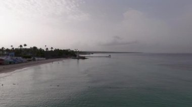 Dominik sahilinin, deniz fenerinin, rıhtımın ve güzel kumlu kumsalın gündoğumunda çekilmiş resmi. Bayahibe, Dominik Cumhuriyeti.