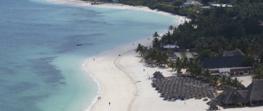 Plaj manzarası yüksek, palmiye ağaçları ve tropikal deniz kıyısında kumlu gök mavisi su. Zanzibar, Afrika, Tanzanya 'da deniz yolculuğu..