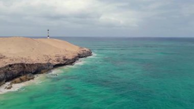 Varandinha kıyısının havadan görünüşü, plaj çevresindeki kayalarla bölünmüş. Kayaların sonunda Boa Vista, Cape Verde 'de bir deniz feneri var..