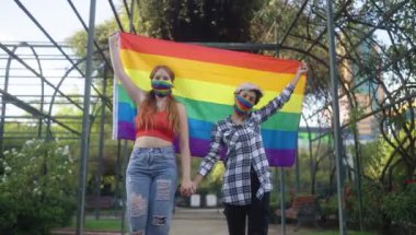 LGBT gururlu gökkuşağı bayrağı taşıyan iki genç kadın