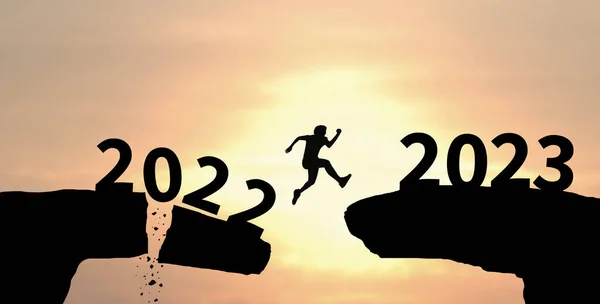 2023年も明けましておめでとう 雲の空の背景に2022年から2023年までの男のシルエットジャンプ崖 — ストック写真