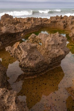 Kayalar tüm bölgeye dağılmış, bazıları büyük ve pürüzlü. Su dalgalı görünüyor. Rabat, Fas, Afrika.