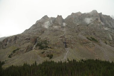 Düşük bulutlar ve su Beartooth Dağları, Montana 'daki kanyon duvarından aşağı akıyor.
