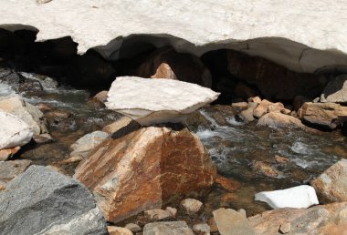 Melting snow cap on a rock in a stream in Beartooth Mountains, Montana