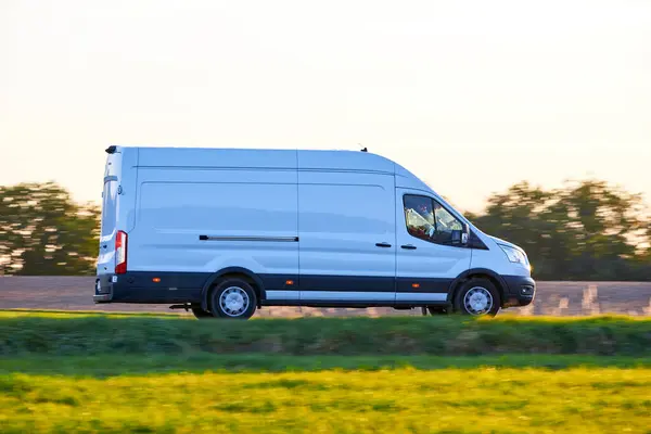 White Van driving fast on a country road. Delivery Van driving at sunset in autumn season.