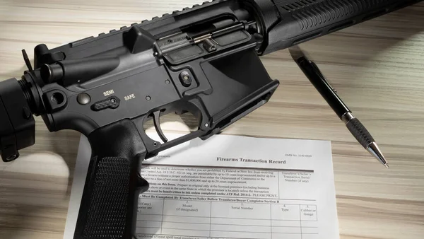 Assault rifle on safe with public domain background check form for its purchase