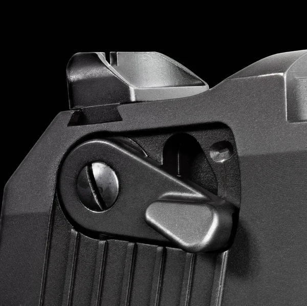 Semi-auto pistol safety and rear sight on a black background