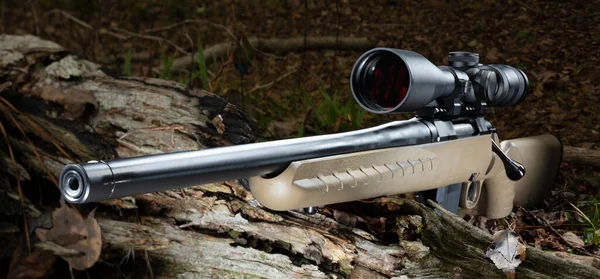High powered hunting rifle with a scope in dark woods