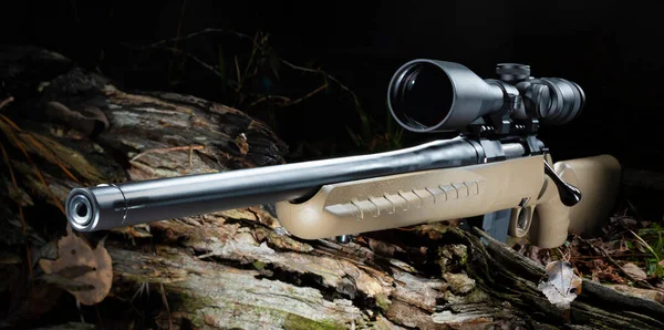 Scope on a bolt action hunting rifle in a dark forest
