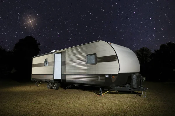 Christmas star rising above a camping trailer on a dark night