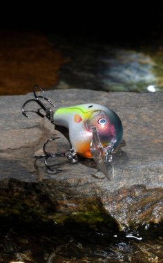 Running water behind an artificial fishing bait on a rock