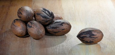 Hala kabuklarında olan cevizler ahşap bir masanın üzerinde.