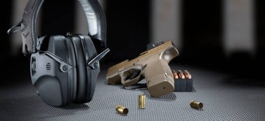 9 mm yarı otomatik tabanca ve mühimmatla atış hattında elektronik işitme korumalar.