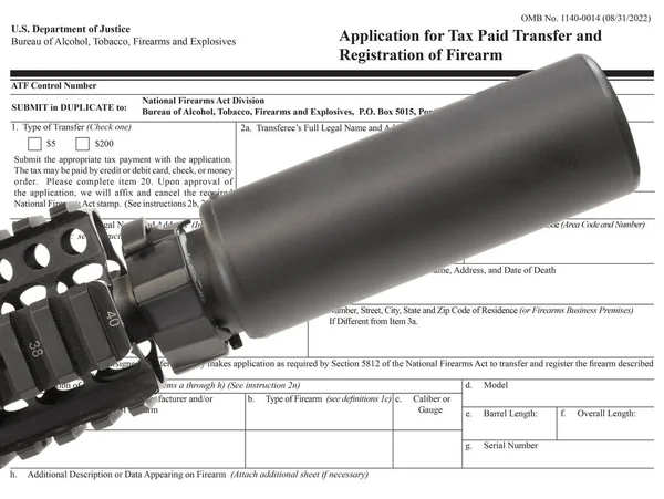 stock image Silencer mounted on an AR-15 with public domain ATF form to own one in the background